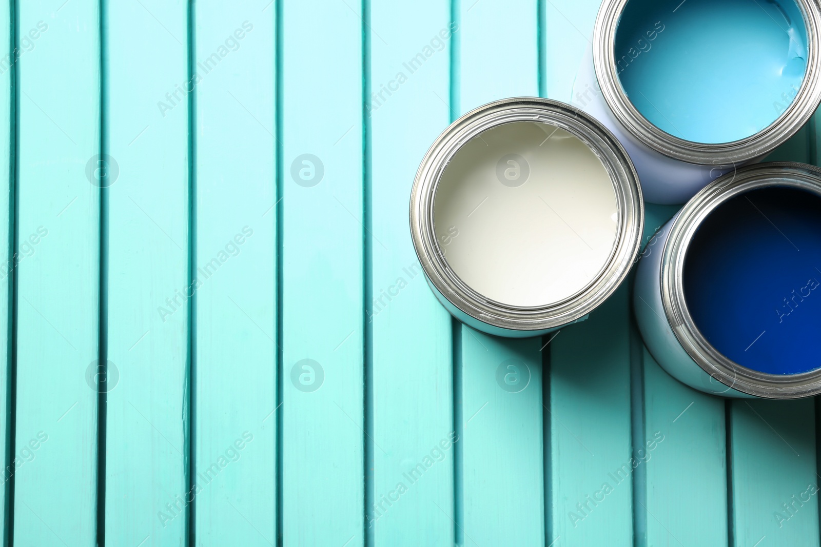 Photo of Colorful paint cans on blue wooden background, top view. Space for text