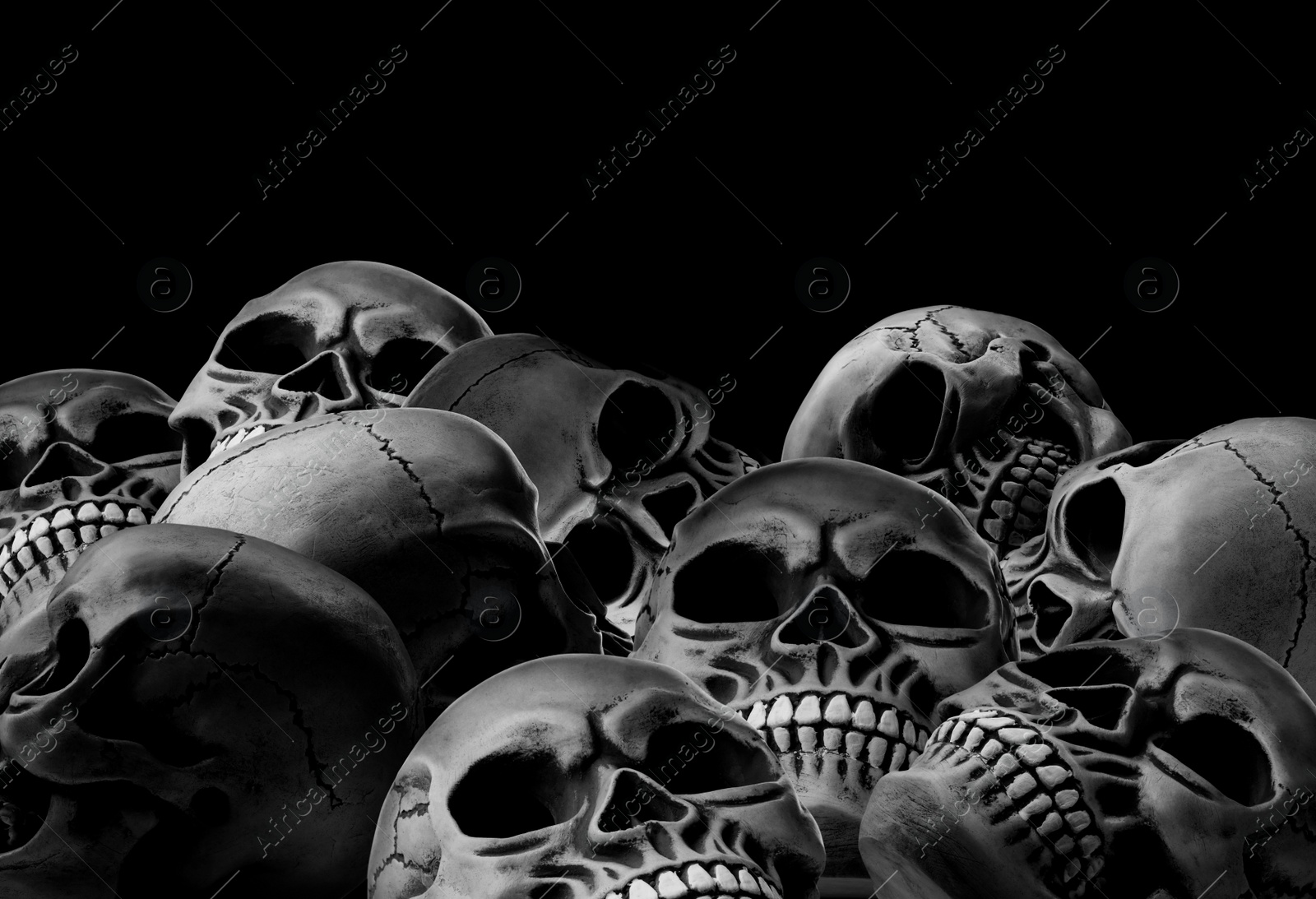 Image of Many scary human skulls on black background, space for text