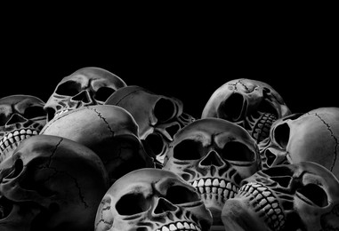 Image of Many scary human skulls on black background, space for text