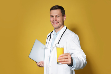 Photo of Nutritionist with glass of juice and laptop on yellow background