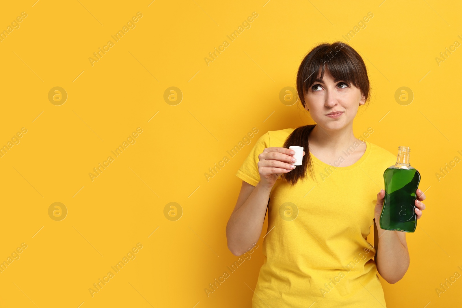 Photo of Young woman using mouthwash on yellow background, space for text