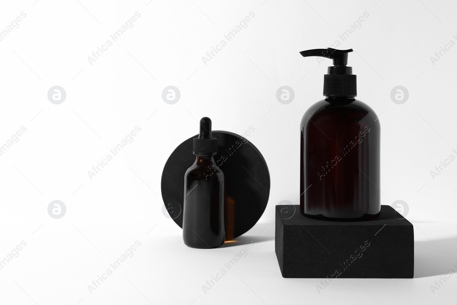 Photo of Bottles with different cosmetic products and podiums on white background, space for text