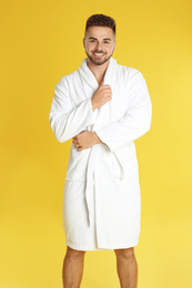 Photo of Happy young man in bathrobe on yellow background