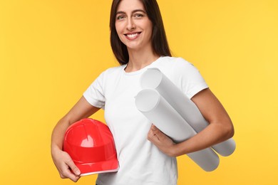 Photo of Architect with hard hat and drafts on yellow background