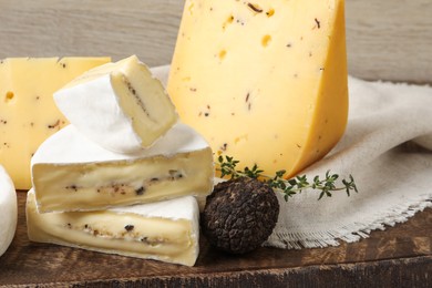 Photo of Different types of cheese and truffles on wooden board, closeup