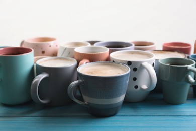 Photo of Many cups of different coffee drinks on light blue wooden table