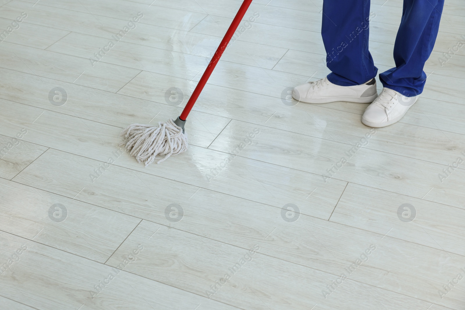 Photo of Man cleaning floor with mop indoors, closeup