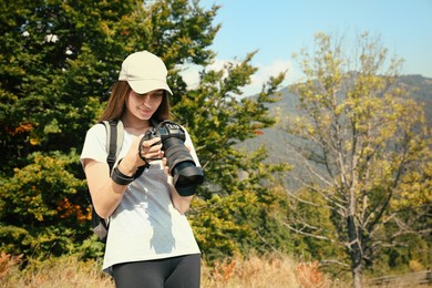 Photo of Professional photographer with modern camera in mountains. Space for text