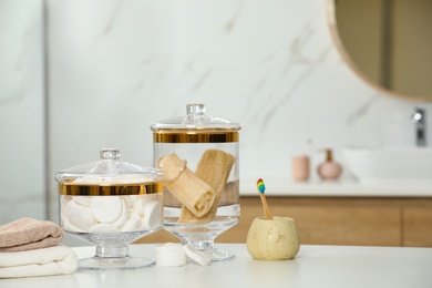 Photo of Composition of glass jar with cotton pads and luffa sponges on table in bathroom. Space for text