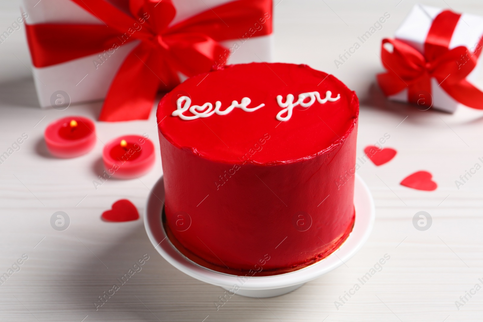 Photo of Bento cake with text Love You, gift boxes, candles and paper hearts on white wooden table. St. Valentine's day surprise