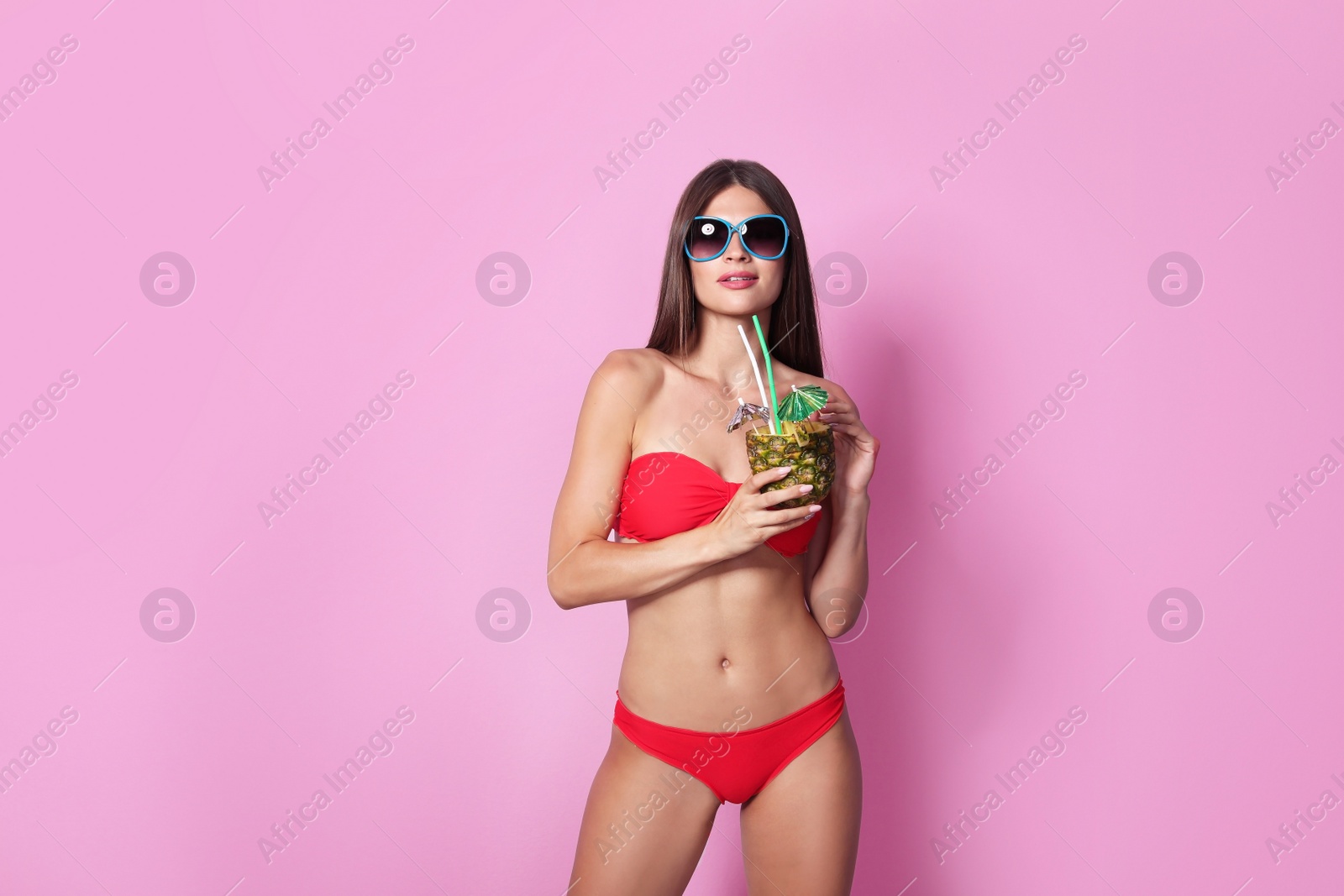 Photo of Sexy young woman in bikini with pineapple cocktail on color background