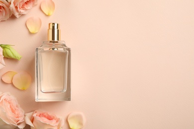 Photo of Bottle of perfume, beautiful flowers and petals on beige background, flat lay. Space for text