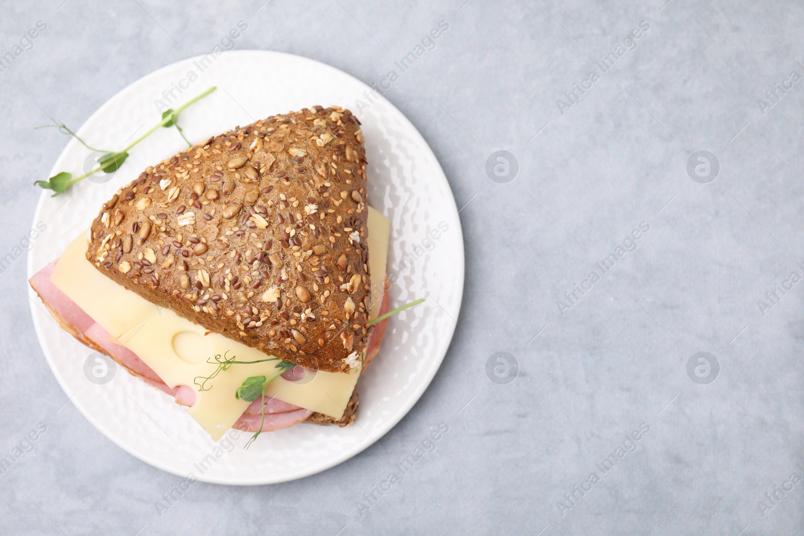 Photo of Delicious sandwich with ham and cheese on light gray table, top view. Space for text