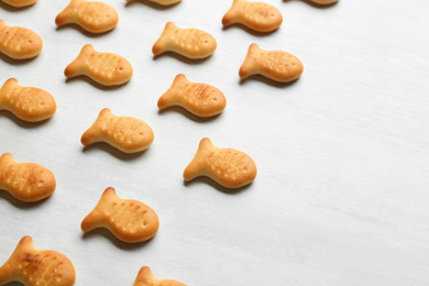 Photo of Delicious goldfish crackers on white table, closeup