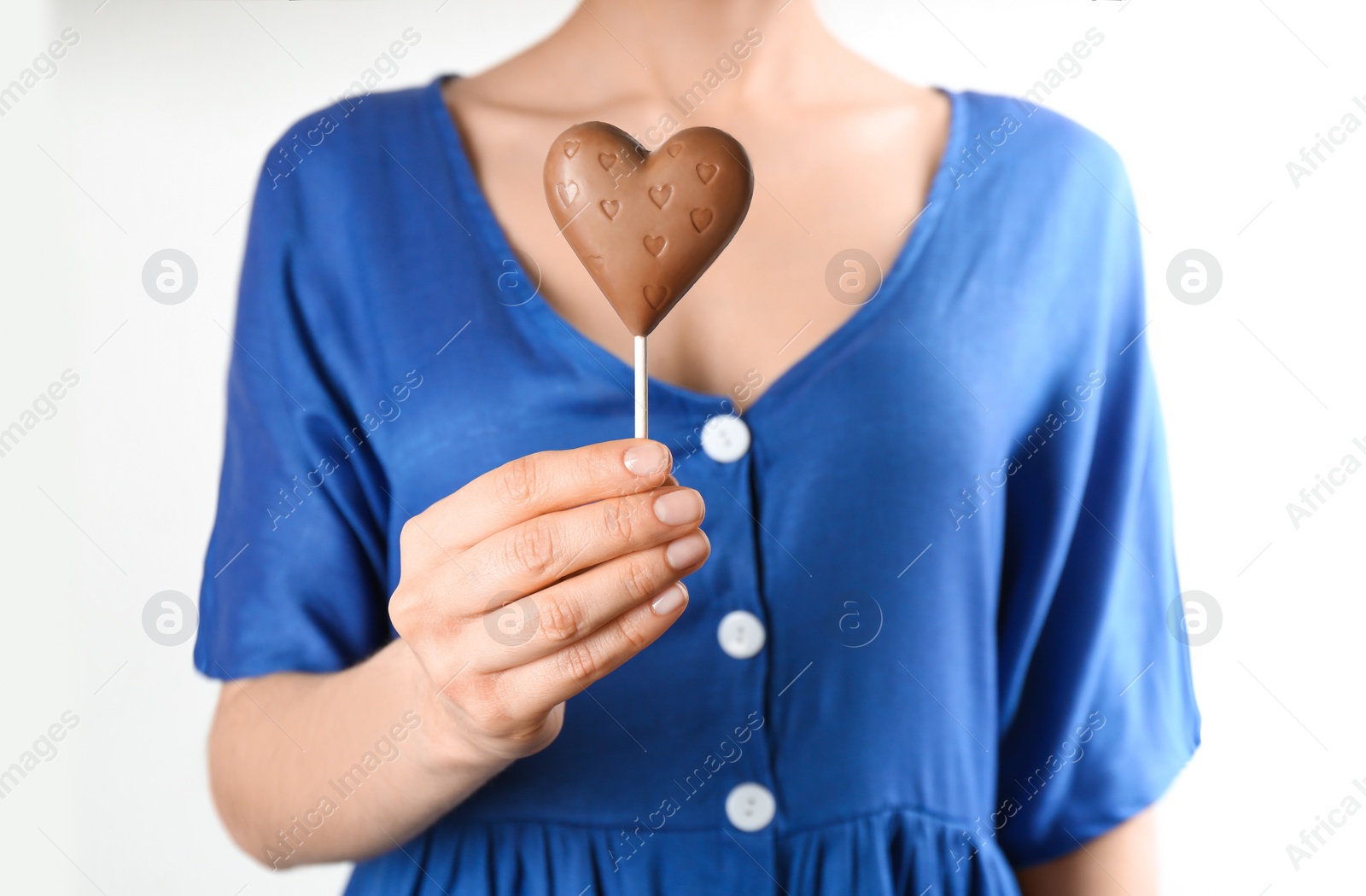 Photo of Woman holding heart shaped lollipop made of chocolate on white background, closeup