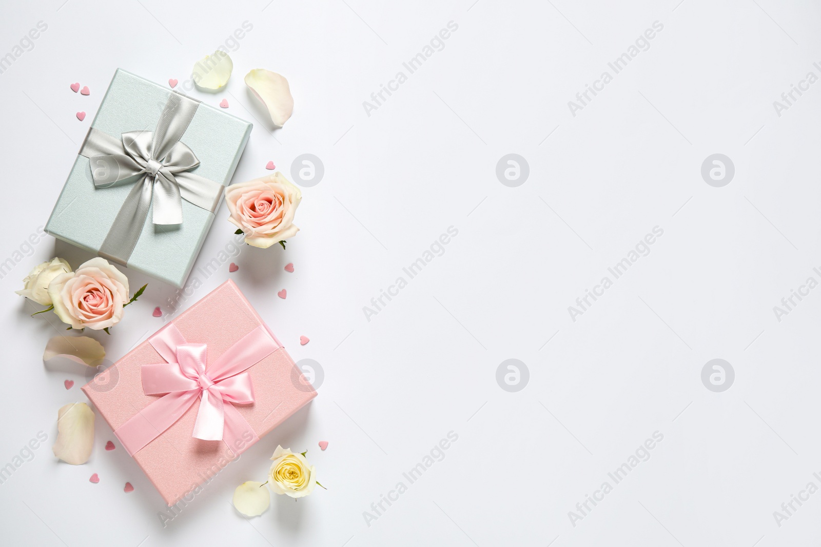 Photo of Elegant gift boxes and beautiful flowers on white background, flat lay. Space for text