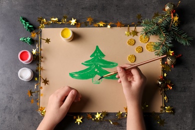 Photo of Little child making Christmas card at black table, top view