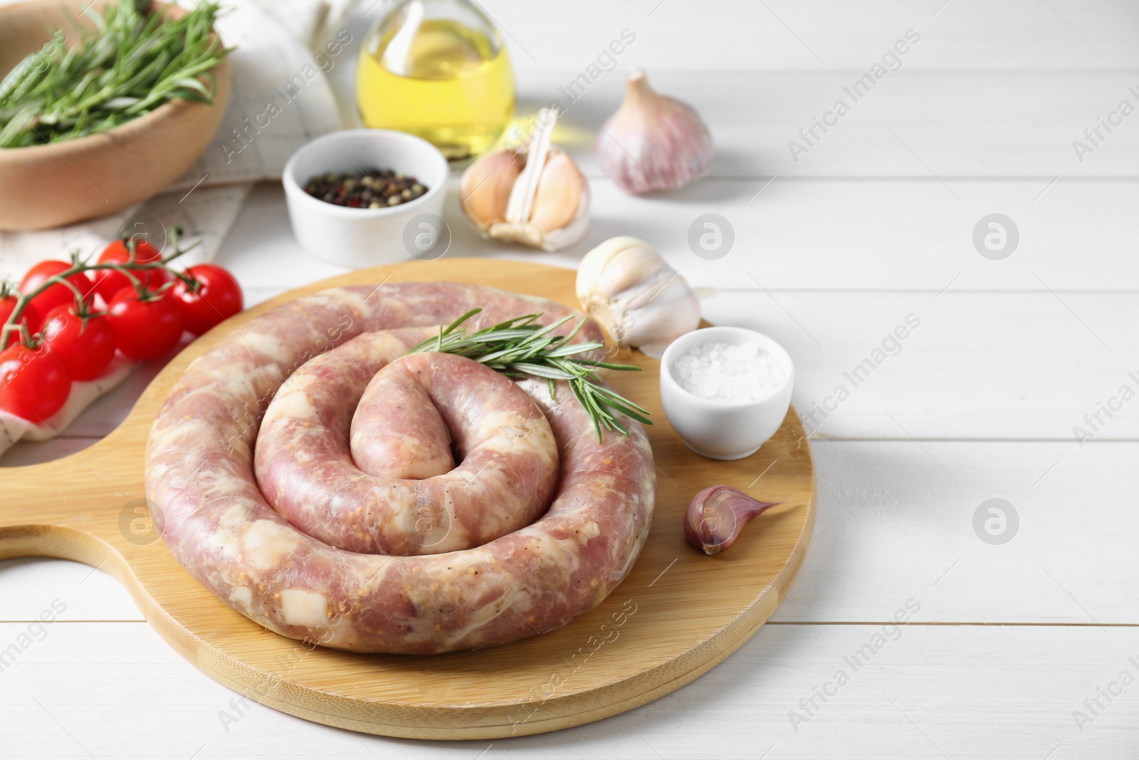 Photo of Raw homemade sausage, spices and other products on white wooden table. Space for text