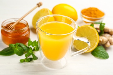 Photo of Immunity boosting drink and ingredients on white table, closeup