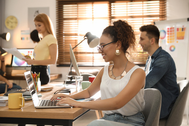 Photo of Happy female designer working with laptop in office