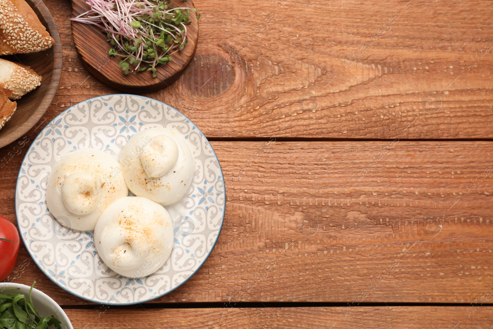 Photo of Delicious burrata cheese on wooden table, flat lay. Space for text