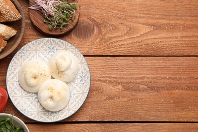 Photo of Delicious burrata cheese on wooden table, flat lay. Space for text