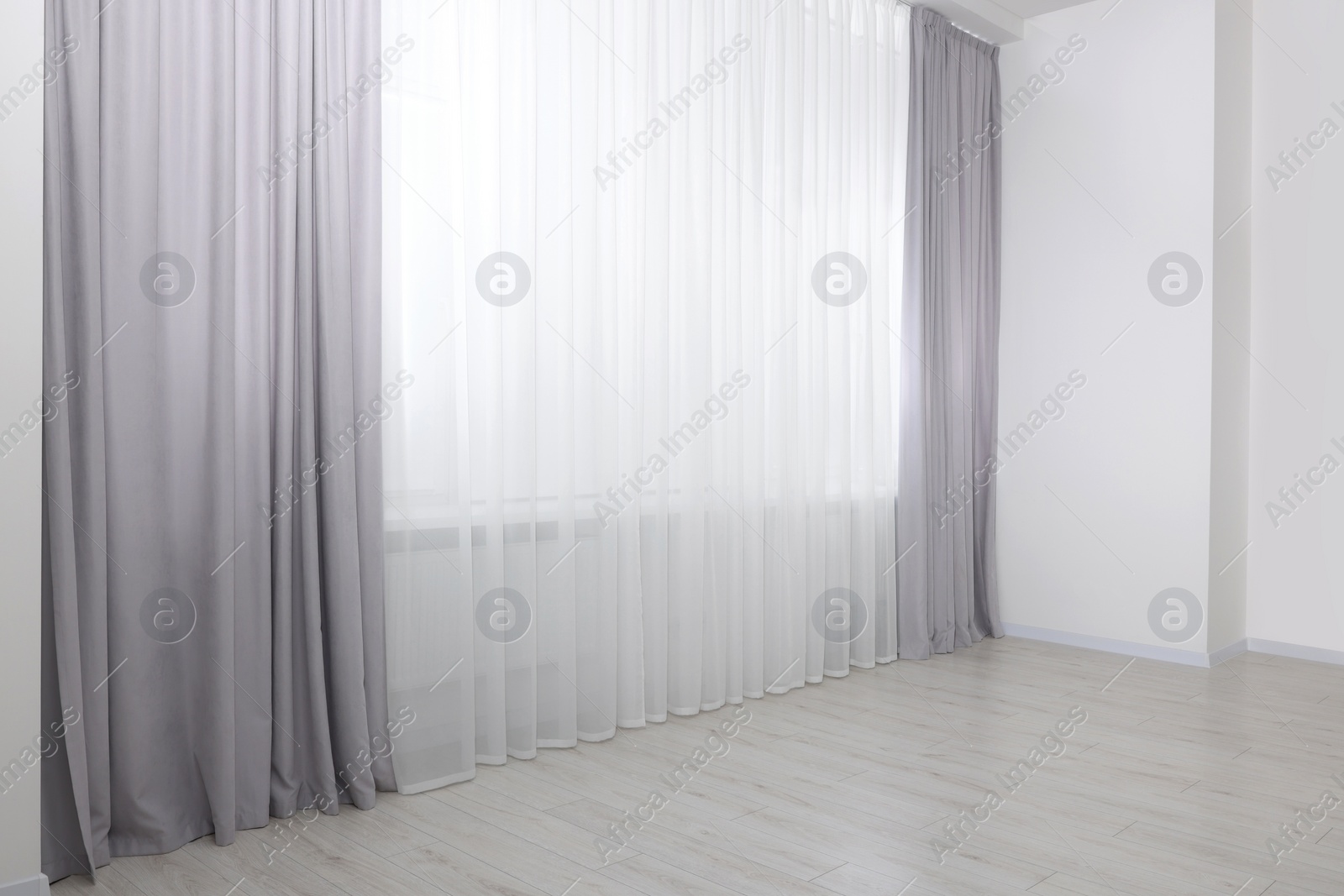 Photo of Light grey window curtains and white tulle indoors