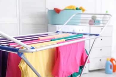 Clean laundry hanging on drying rack indoors, closeup