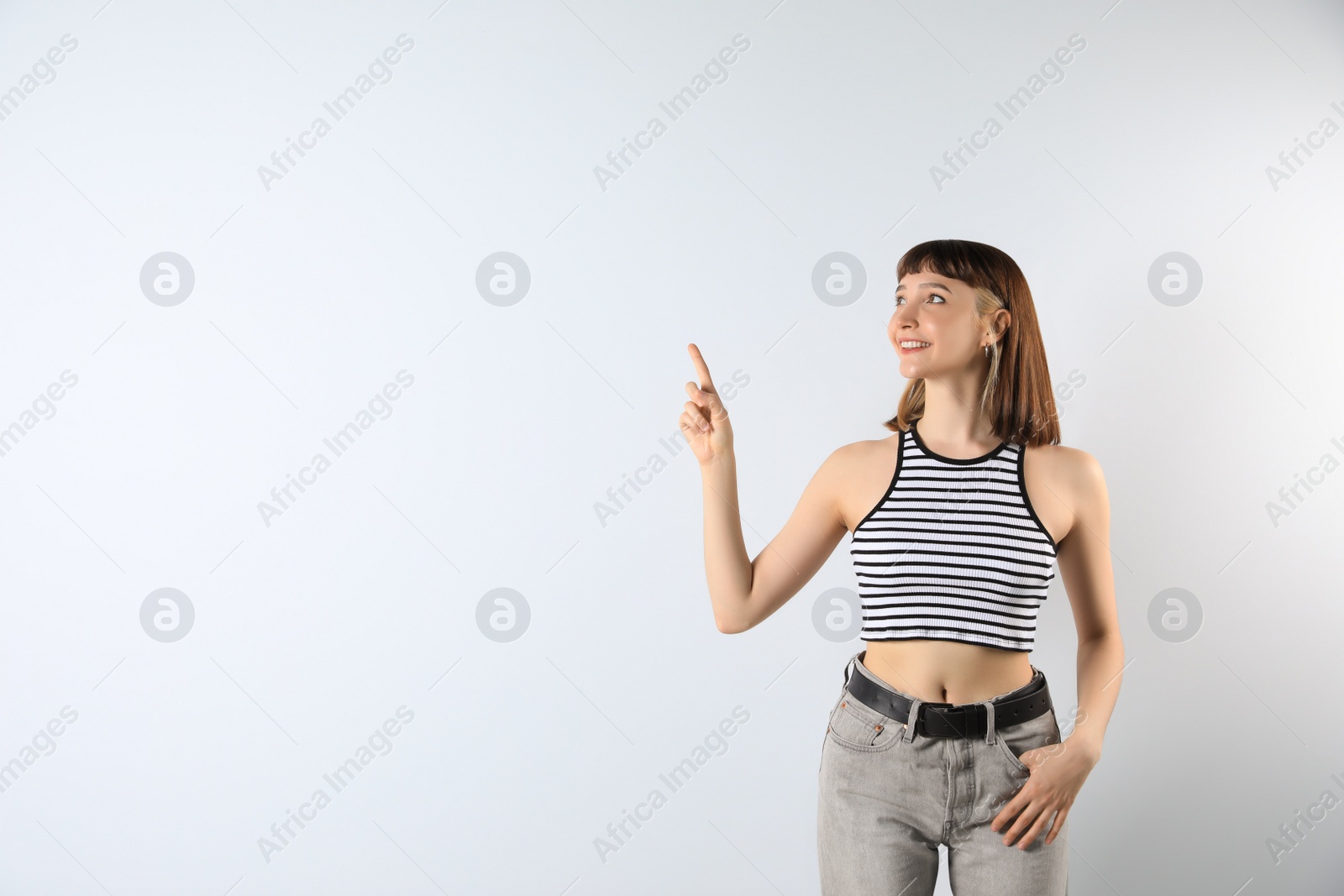 Photo of Beautiful young girl pointing on white background. Space for text