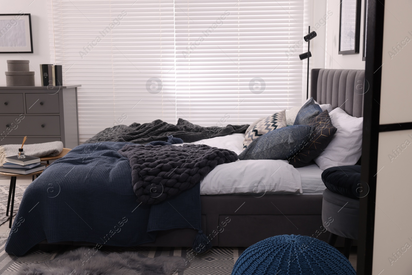 Photo of Large comfortable bed with soft pillows and blankets in room. Home textile