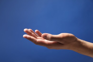 Man holding something in hand on blue background, closeup