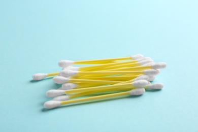 Pile of cotton swabs and space for text on color background