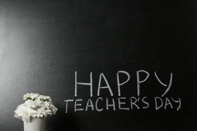 Photo of Vase of flowers near blackboard with inscription HAPPY TEACHER'S DAY, space for text