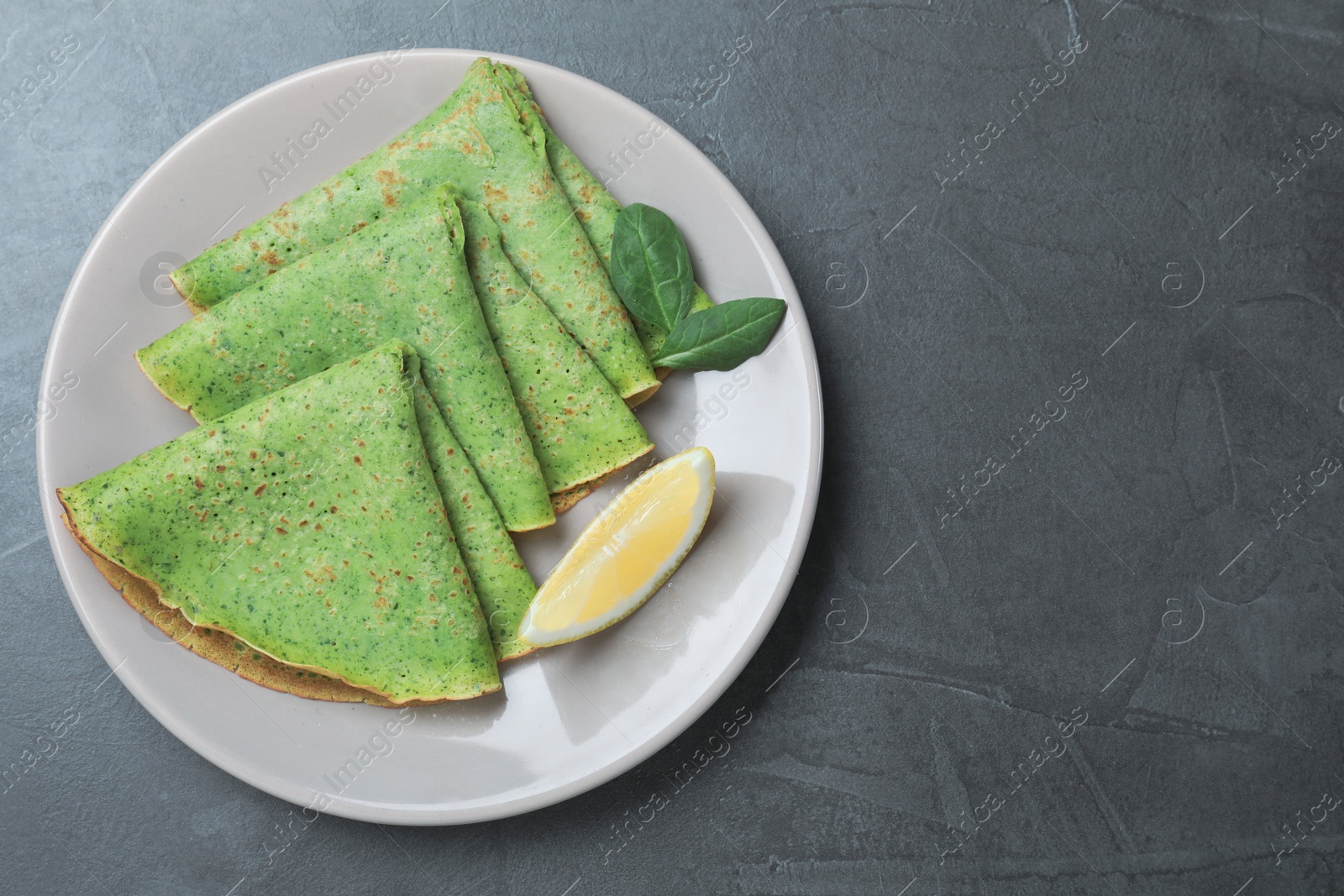 Photo of Tasty spinach crepes served on grey table, top view. Space for text