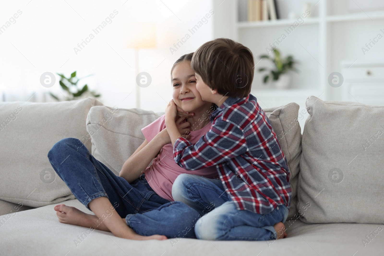 Photo of Happy brother and sister spending time together on sofa at home