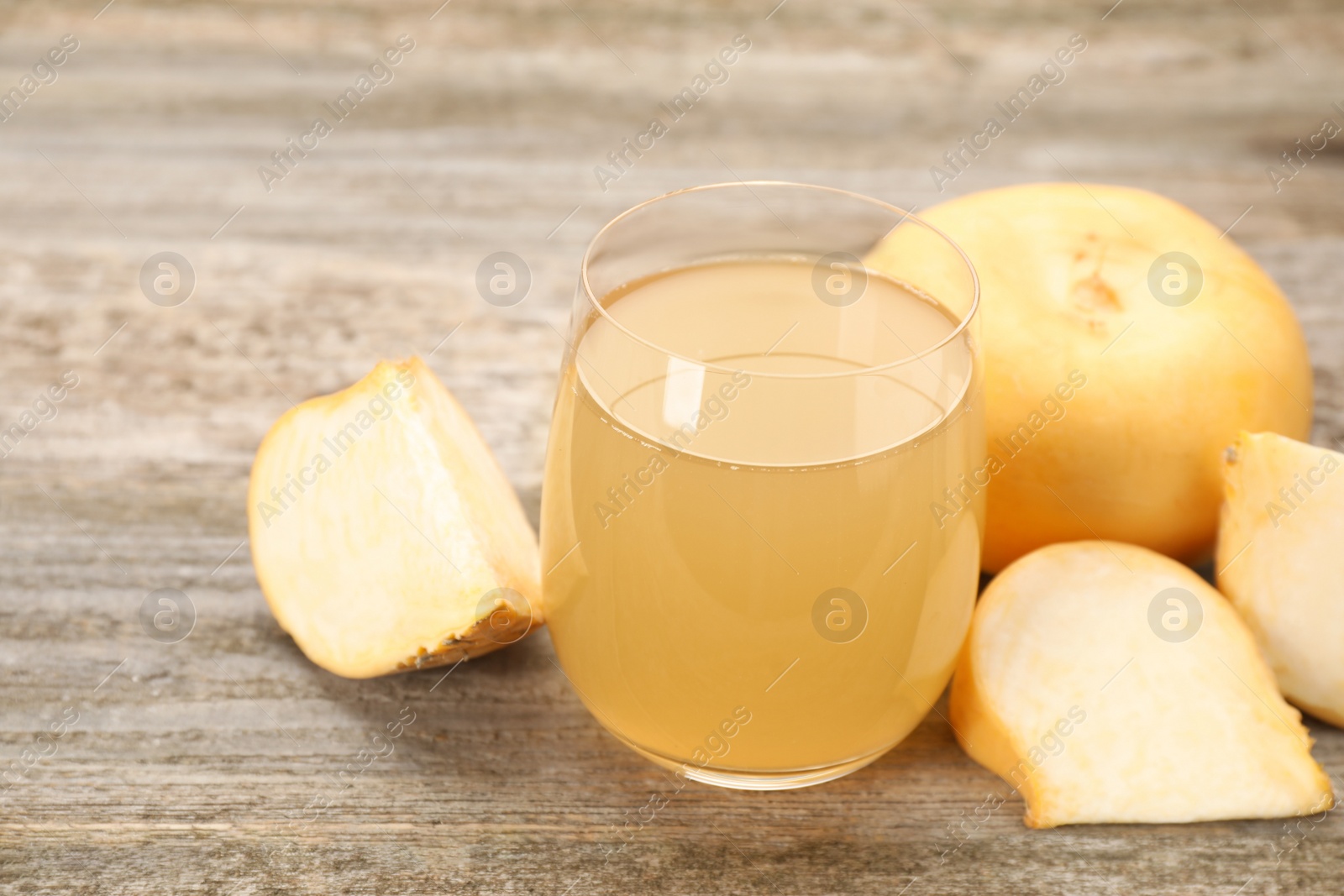 Photo of Glass of freshly made turnip juice on wooden table, closeup