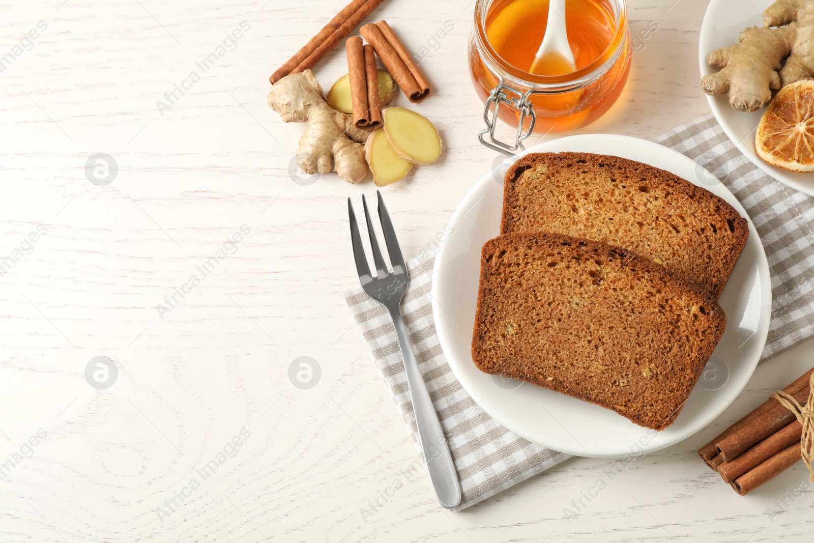 Photo of Fresh gingerbread cake slices served on white wooden table, flat lay. Space for text