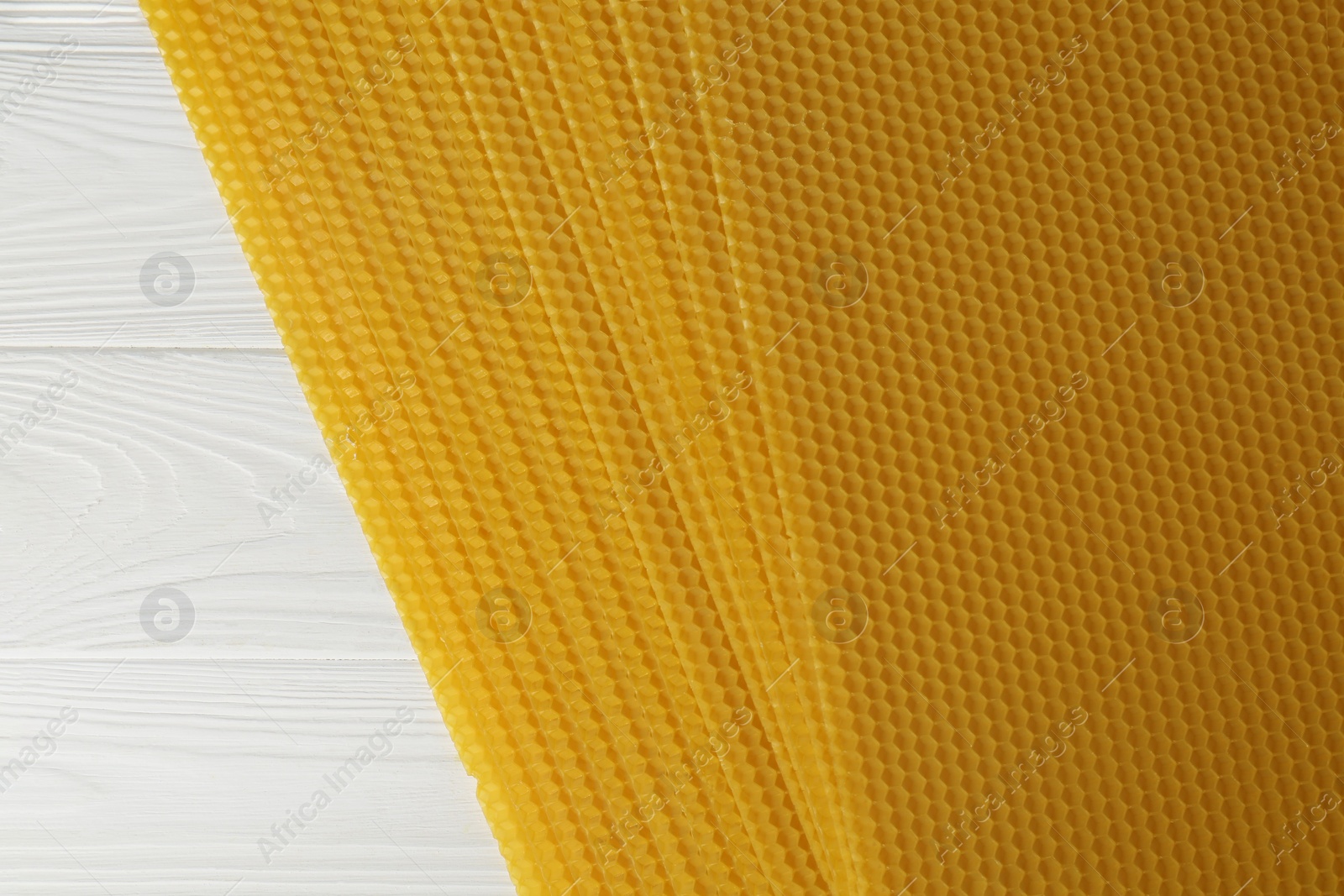 Photo of Natural organic beeswax sheets on white wooden table, top view. Space for text