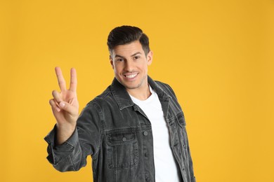 Photo of Man showing number two with his hand on yellow background