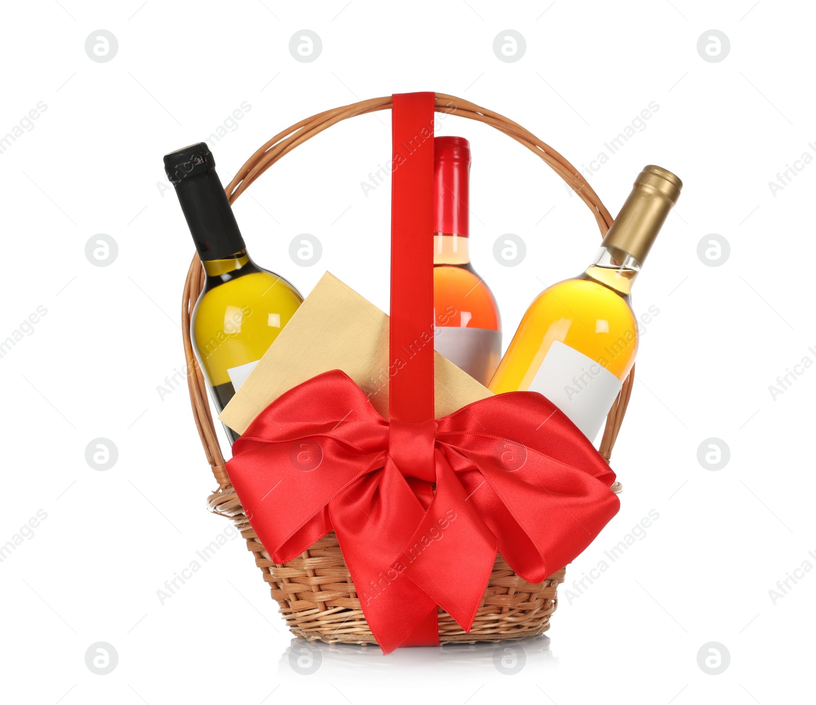 Photo of Bottles of wine and greeting card in wicker basket with red bow isolated on white