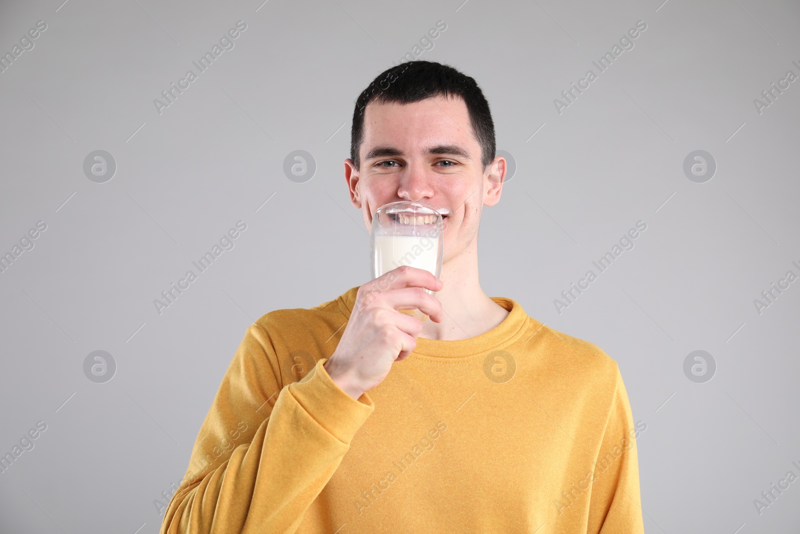 Photo of Milk mustache left after dairy product. Man drinking milk on gray background