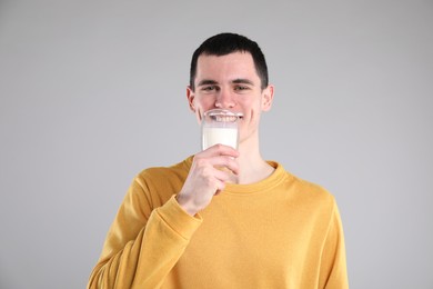 Milk mustache left after dairy product. Man drinking milk on gray background