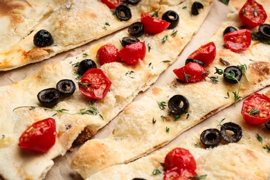 Photo of Delicious focaccia bread with olives and tomatoes, closeup