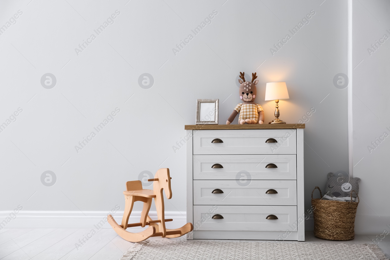 Photo of Modern white chest of drawers near light wall in child room, space for text. Interior design