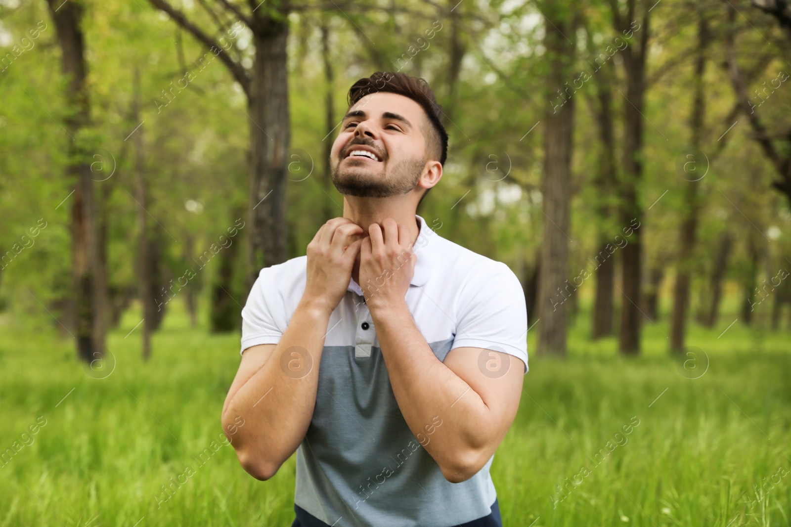 Photo of Young man scratching neck outdoors. Seasonal allergy