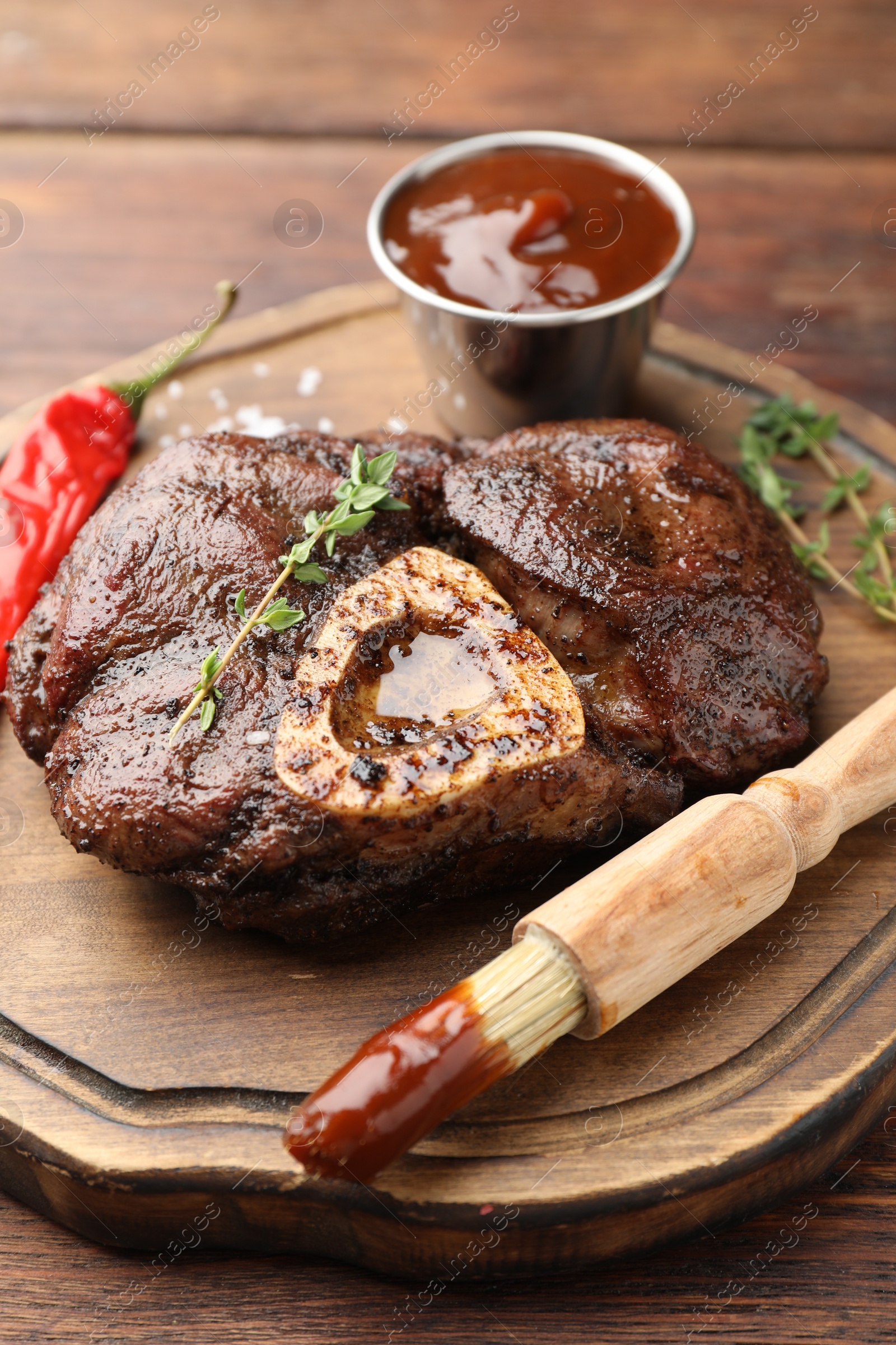 Photo of Delicious roasted beef meat served with sauce and spices on wooden table, closeup