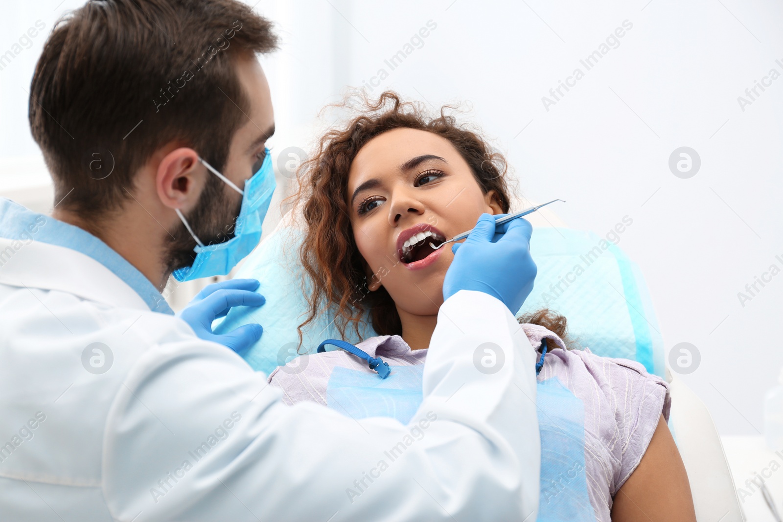 Photo of Dentist examining African-American woman's teeth with probe in hospital