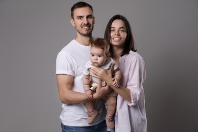 Photo of Happy family. Couple with their cute baby on grey background