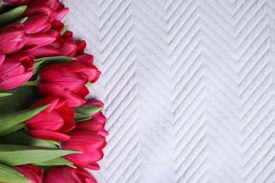 Many beautiful tulips on white fabric, top view. Space for text