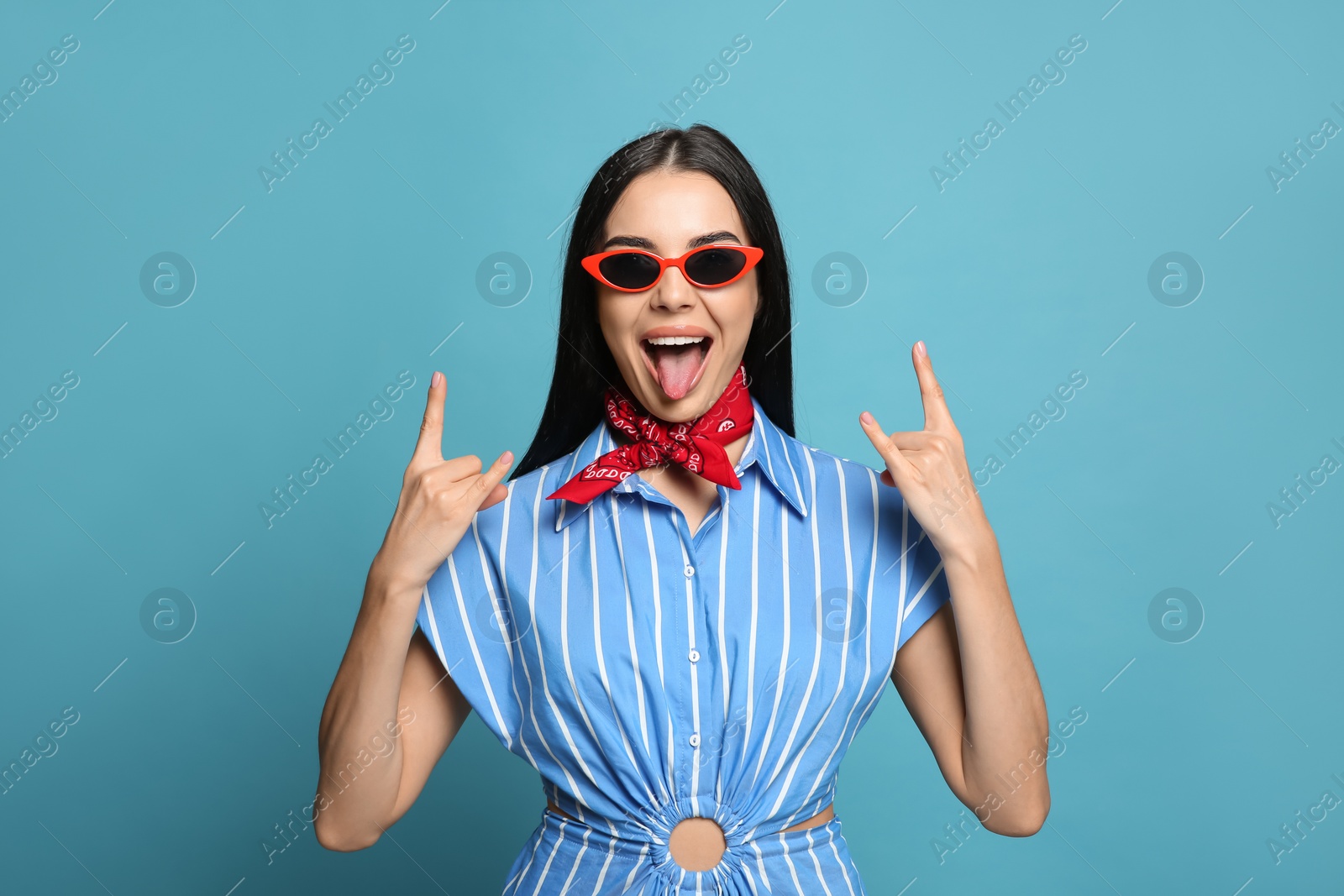 Photo of Fashionable young woman in stylish outfit with bandana on light blue background